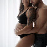 intimate couples maternity session in arizona on curtain backlit backdrop